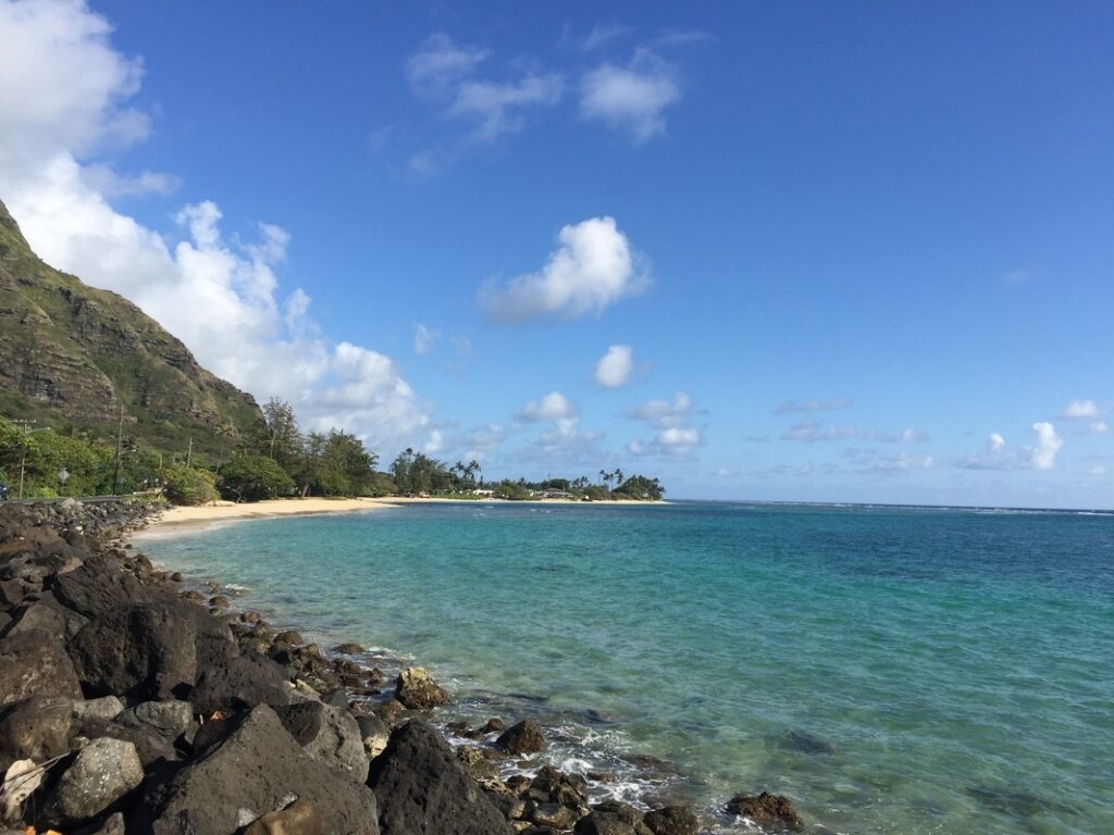 Clear blue ocean meets rocky shore under a bright sky.