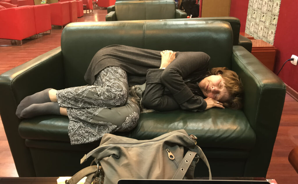 Person curled up sleeping on a green couch.
