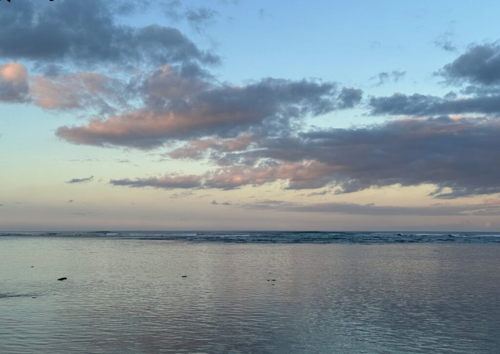 Calm sea under a cloudy sky at sunset.
